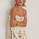 Woman with short, wavy blonde wig from Hidden Secrets Wigs Sheena collection.